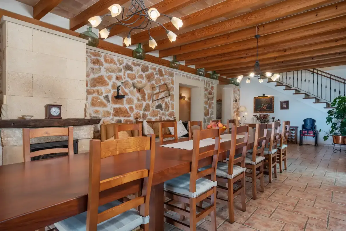 Comedor con una larga mesa de madera bajo vigas vistas.