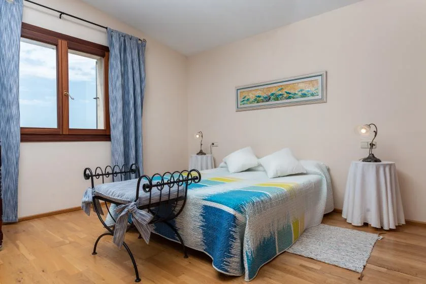 Un dormitorio con una cama vestida de azul y blanco junto a una ventana con cortinas.