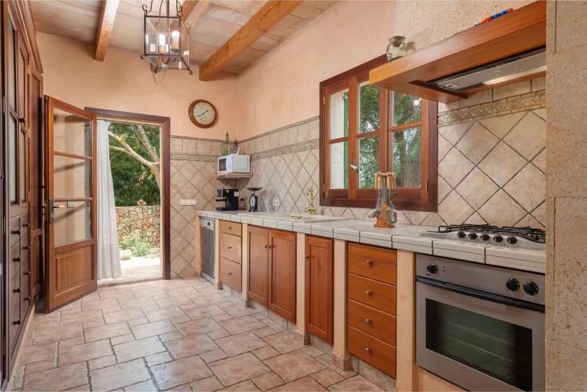 Una cocina con gabinetes de madera, un salpicadero de azulejos y una ventana con vista a la vegetación.