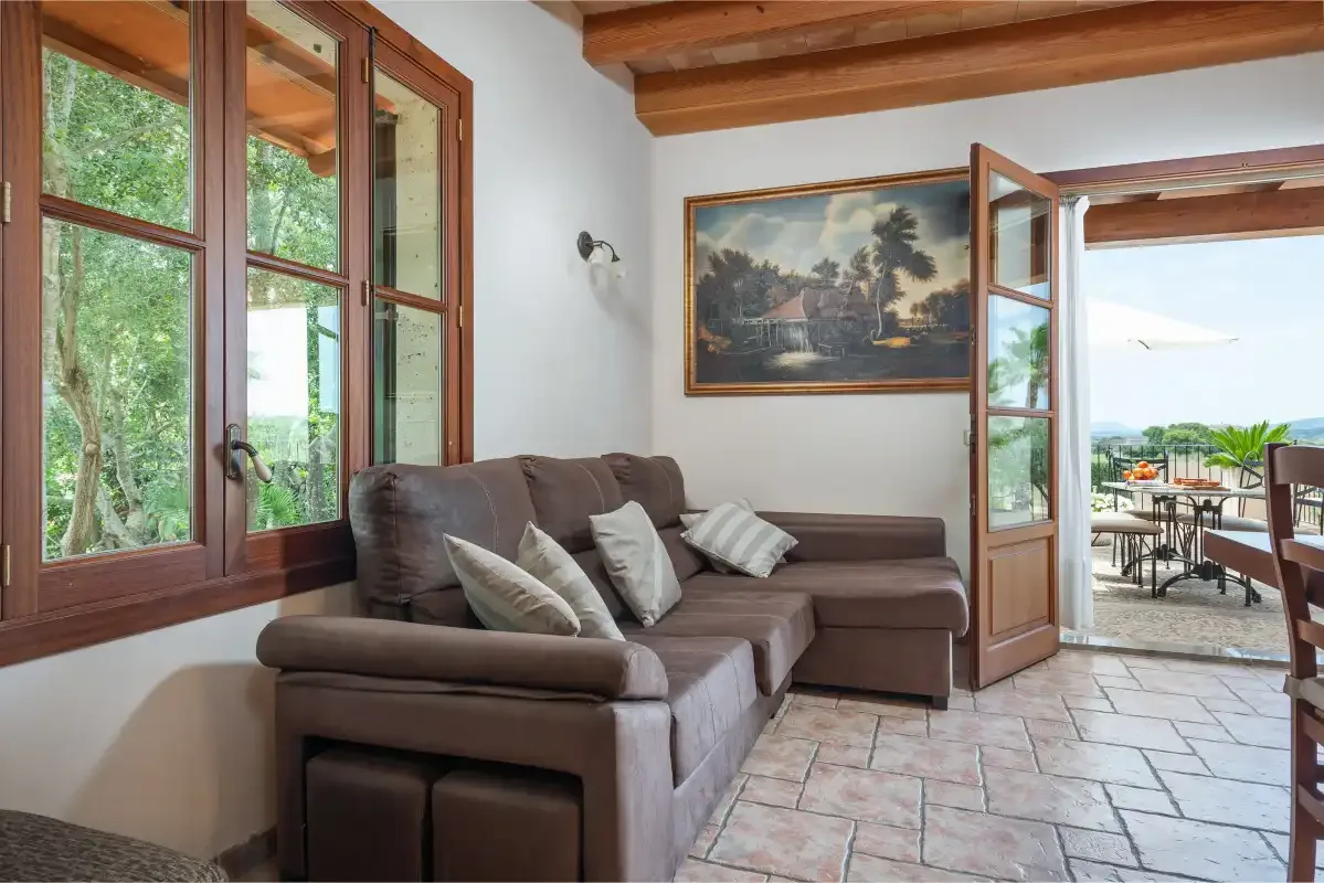 Una sala de estar con un sofá seccional marrón y una puerta abierta a la terraza.