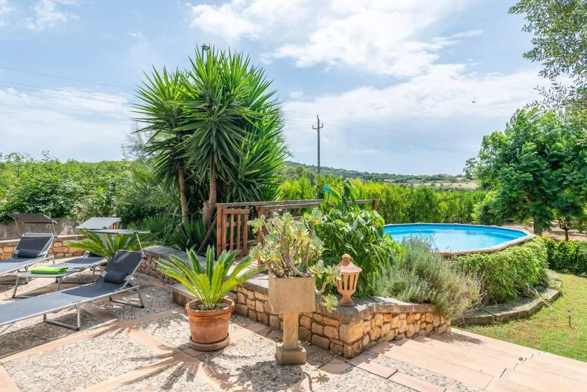 Una piscina al aire libre está junto a un jardín de piedra y asientos en el patio.