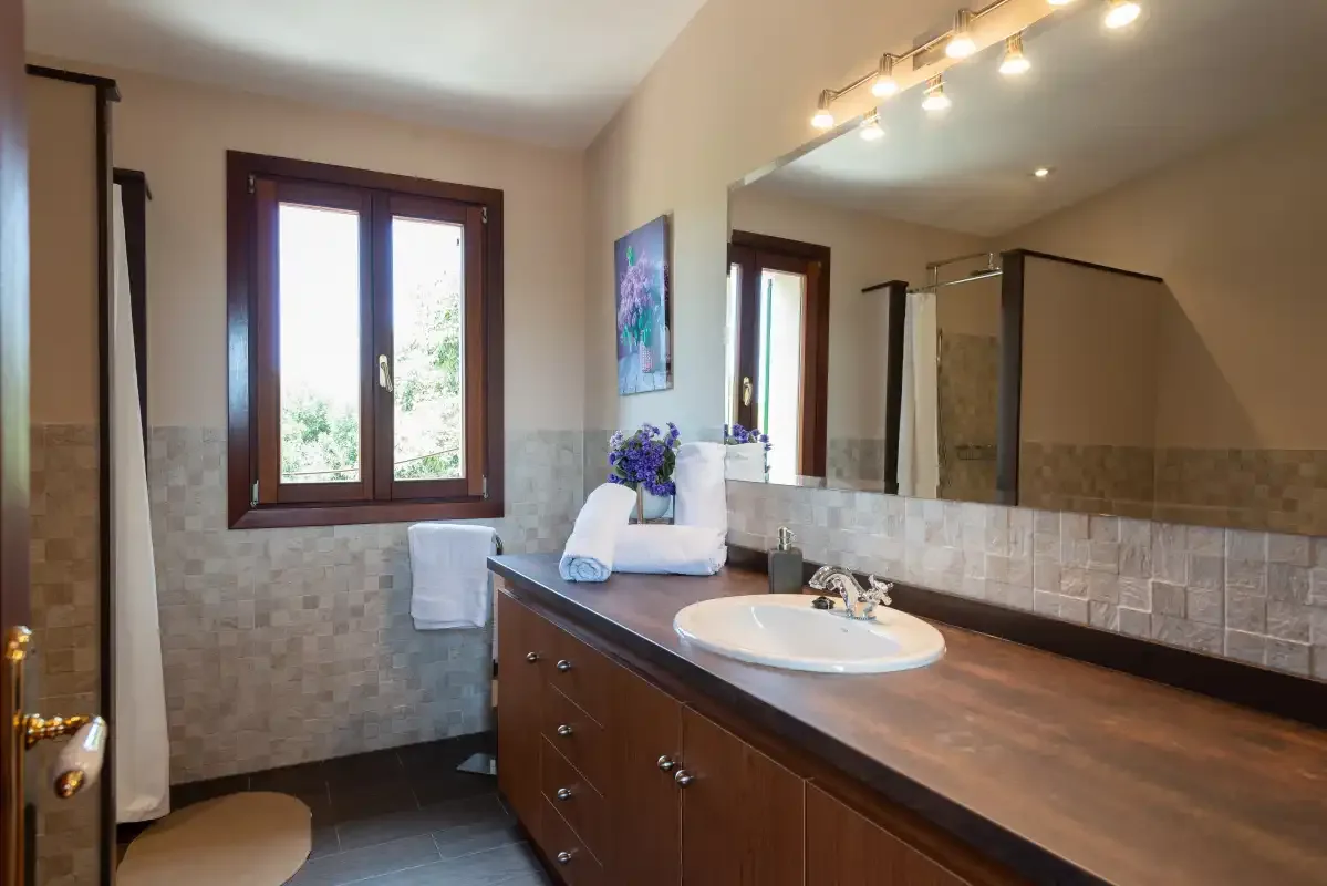 Un lavabo de baño con espejo está junto a una ventana.