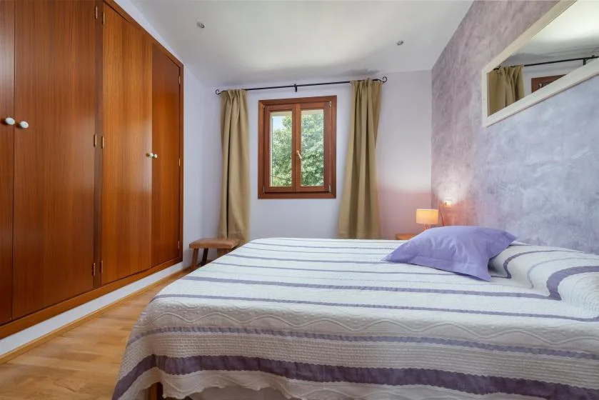 Un dormitorio con una cama grande, armarios de madera y una ventana con cortinas.
