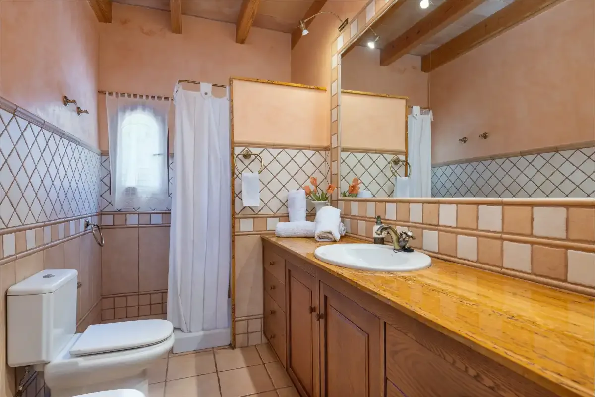Un baño con un mueble largo, lavabo y zona de ducha con cortina.