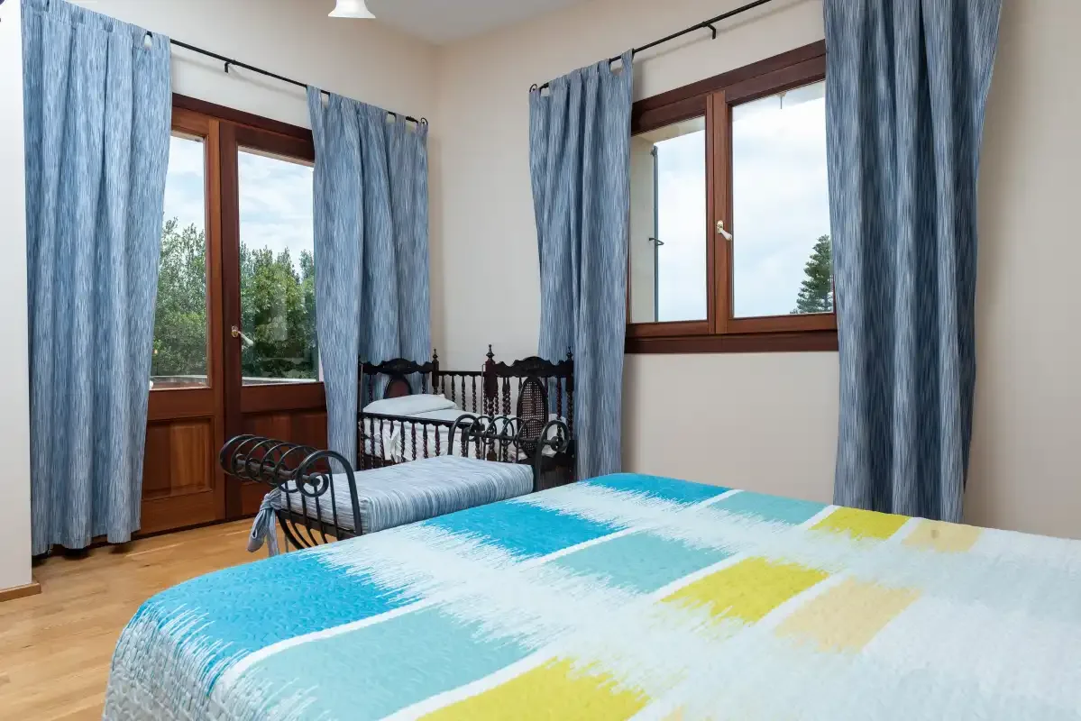 Un dormitorio con una colcha colorida, una cama individual y cortinas azules.