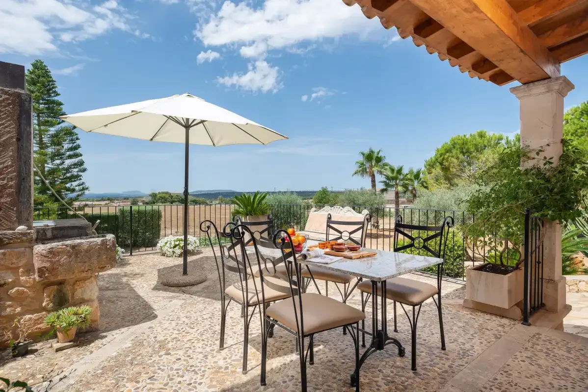 Una zona de comedor al aire libre con mesa y sombrilla da al campo.
