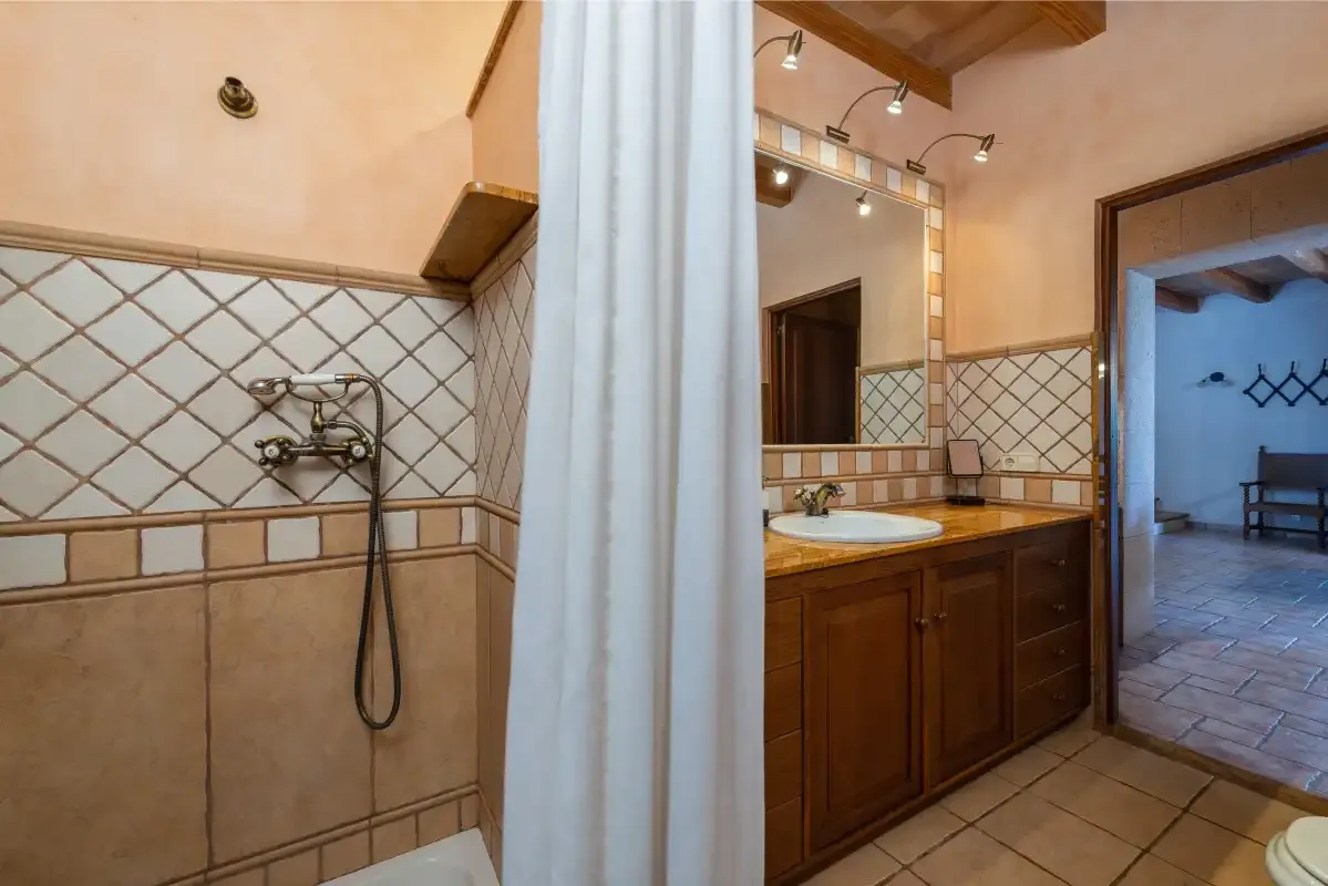 Un baño con ducha junto a un mueble de madera y un espejo.