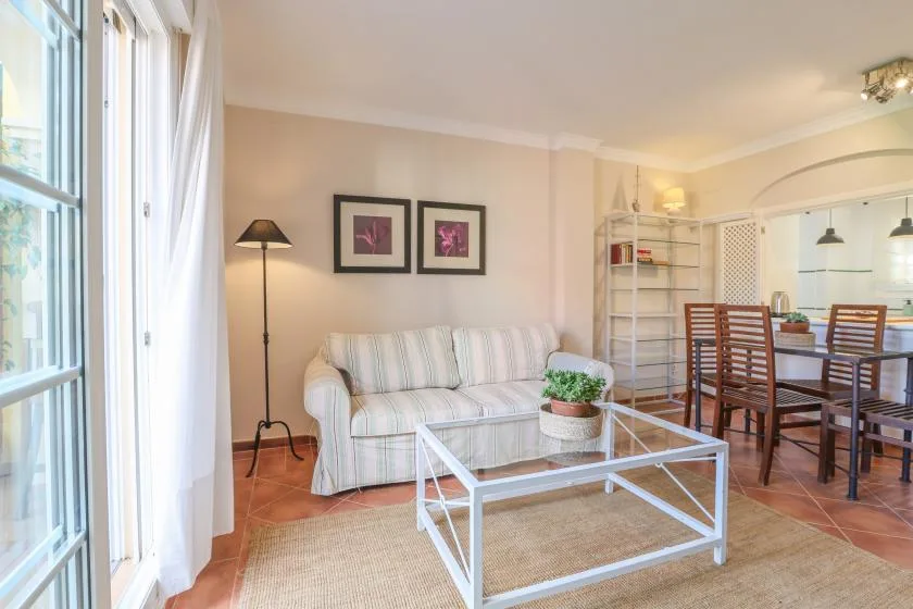 A bright living and dining area with seating, a glass coffee table, and a dining table.