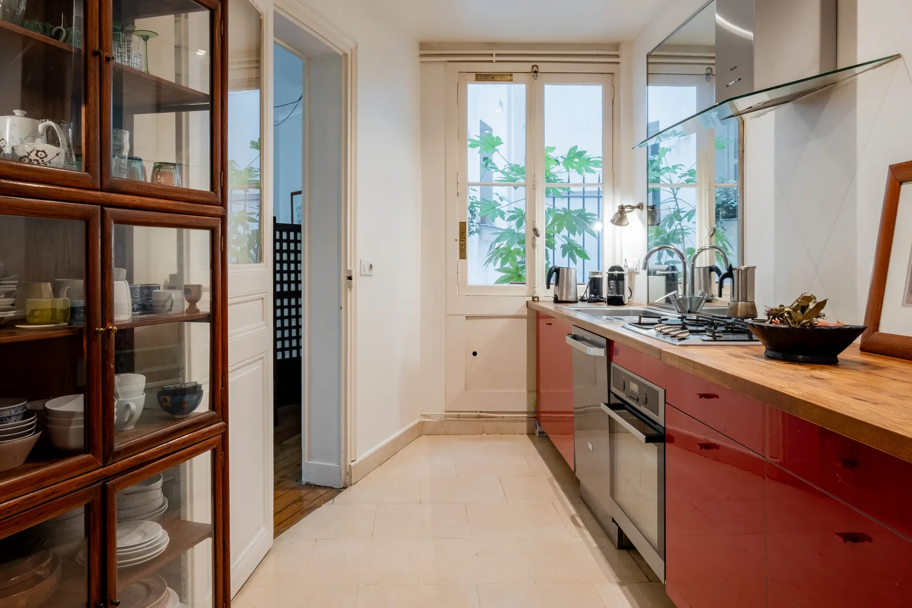 A bright kitchen with red cabinets, a wooden countertop, and a window.