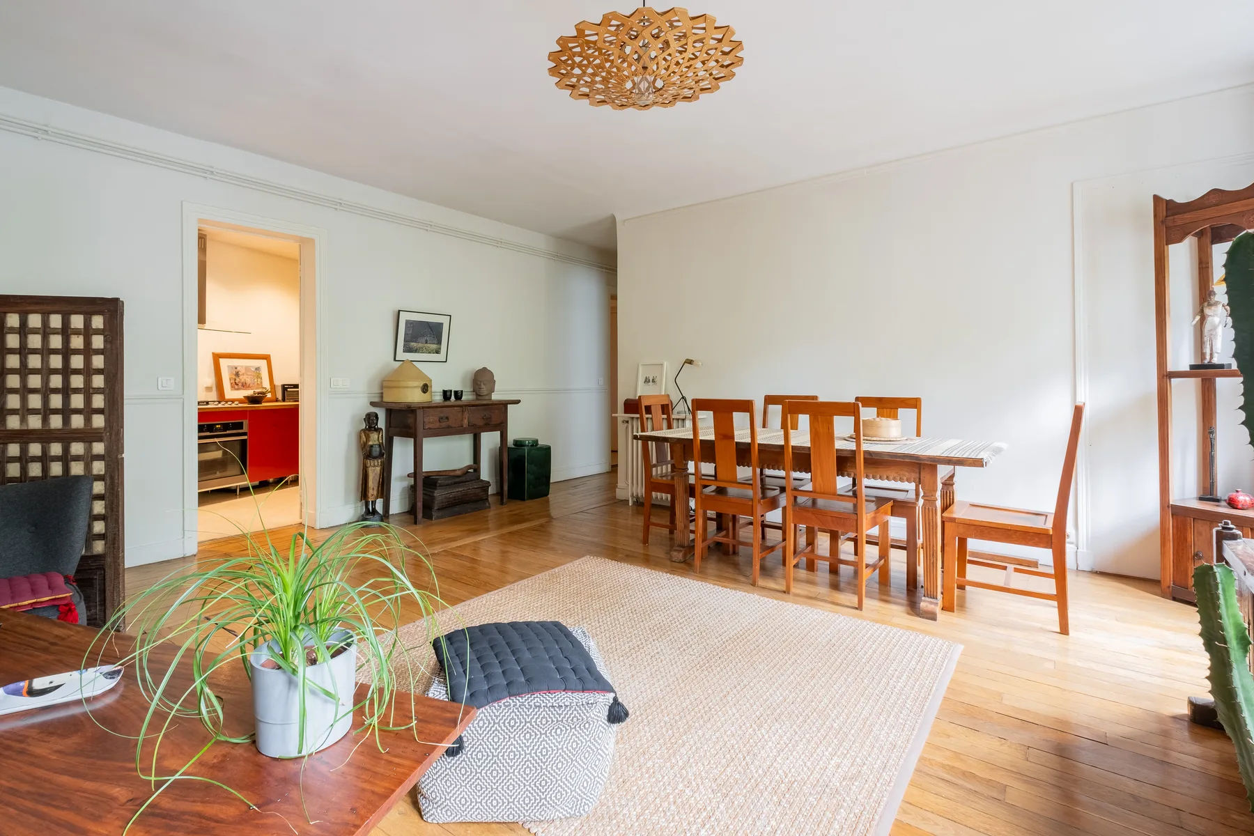 A bright dining room with a wooden table and chairs beside a fireplace.