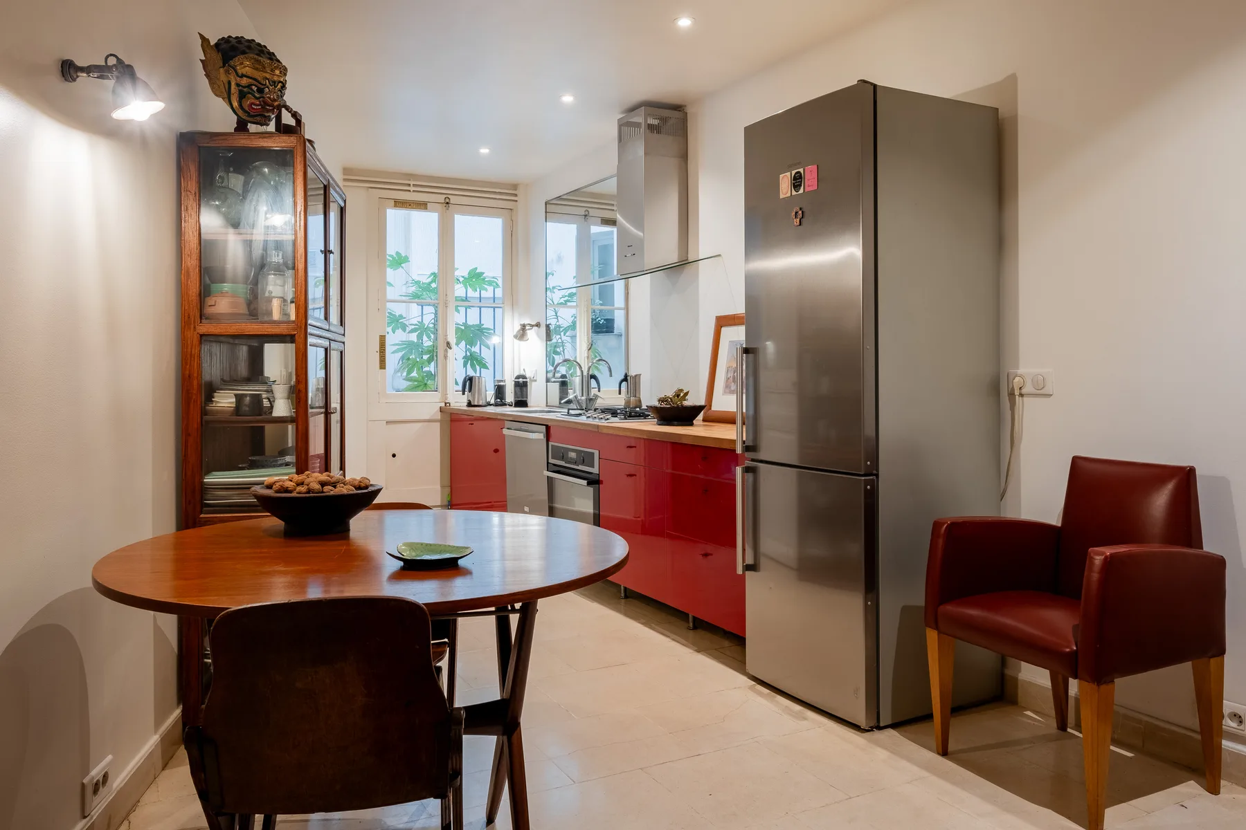 A kitchen with red cabinets, a refrigerator, and a dining table.