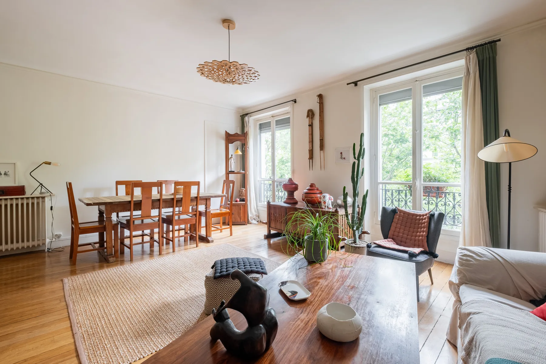 A bright living and dining room with a wooden table and large windows.