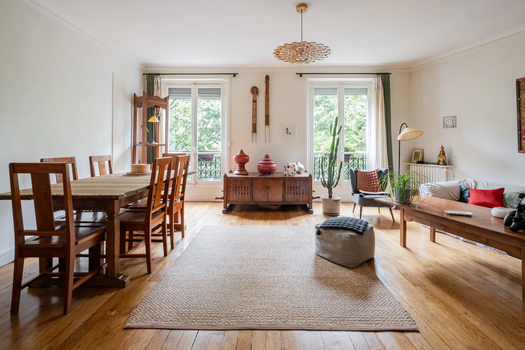 A bright living and dining room with wooden seating and large windows.