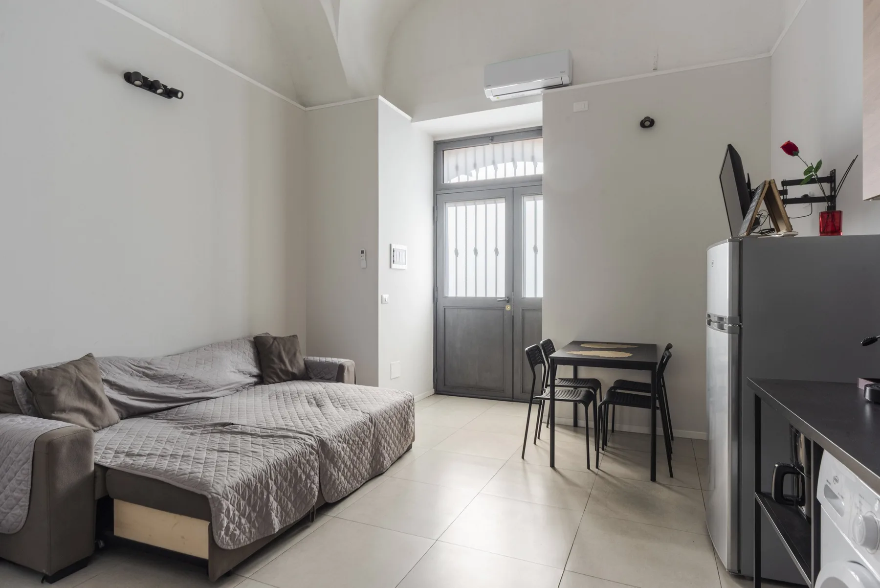 A compact living and dining area with seating, a table, and a tall windowed door.