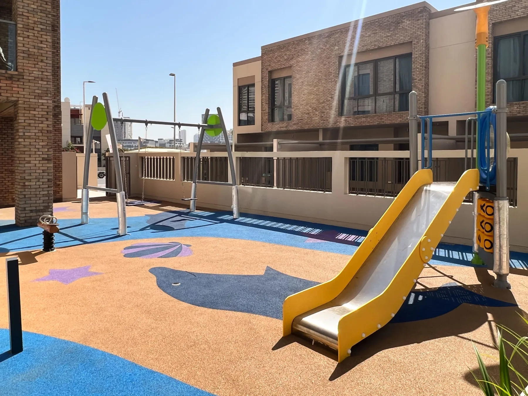 Un patio de juegos al aire libre con un tobogán amarillo y equipo para trepar.
