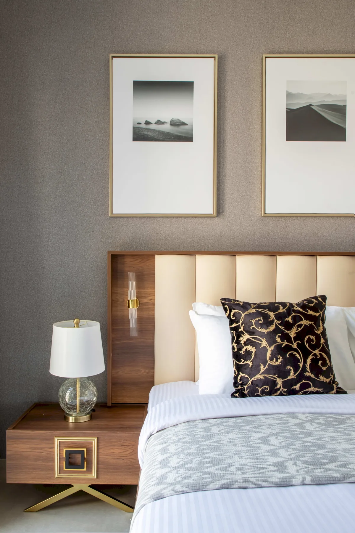 Un dormitorio con una cama bien tendida, cojines estampados y cuadros de paisajes.