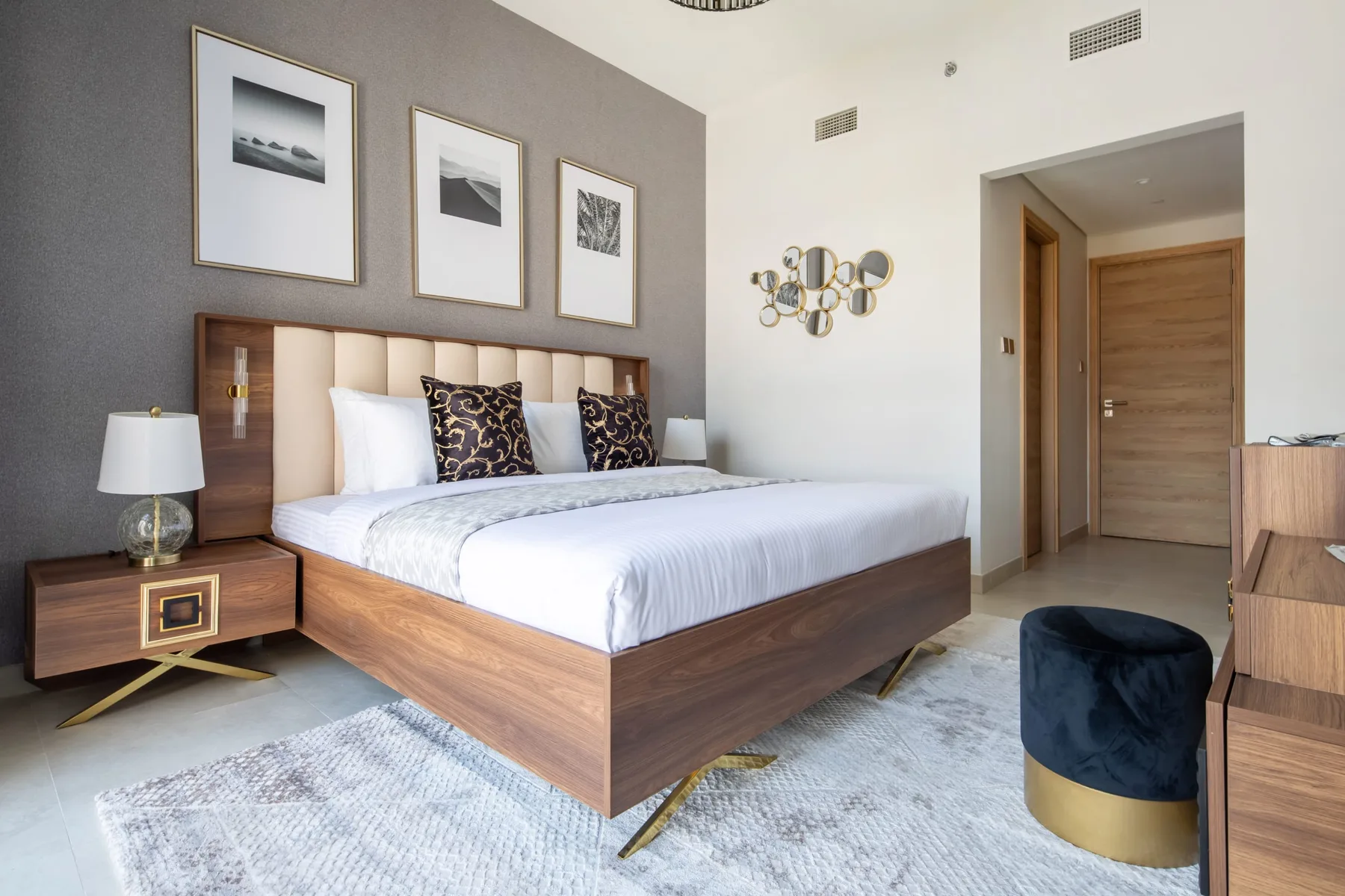Un dormitorio con una cama tendida, cuadros enmarcados y una mesita de noche.
