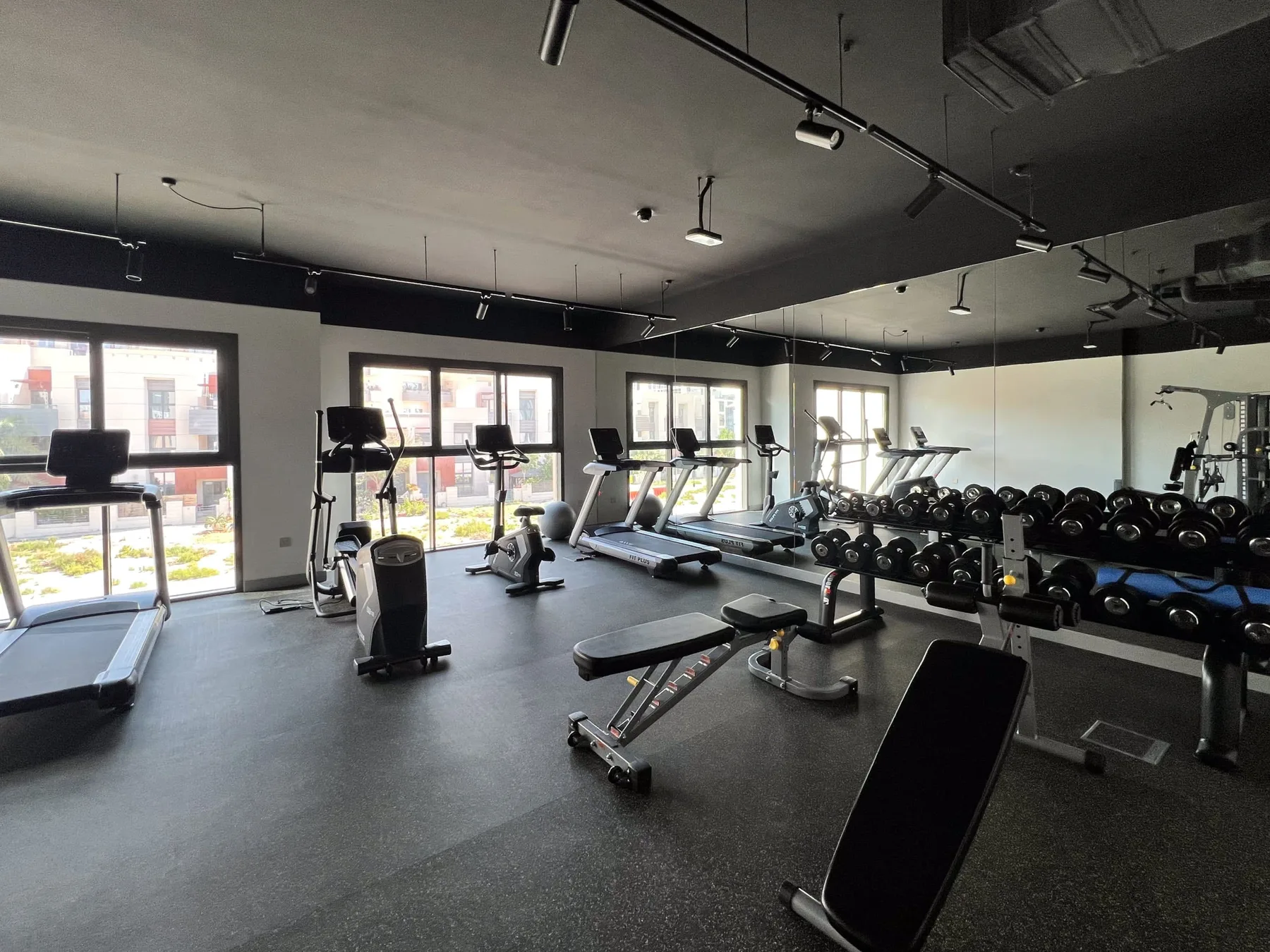 Un gimnasio con máquinas de ejercicio, pesas y bancos de entrenamiento.