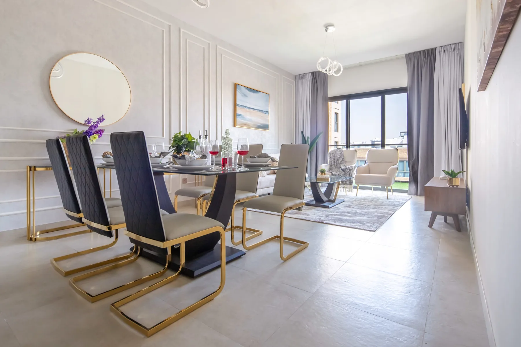 Un luminoso comedor y sala de estar con una mesa y asientos junto a grandes ventanales.