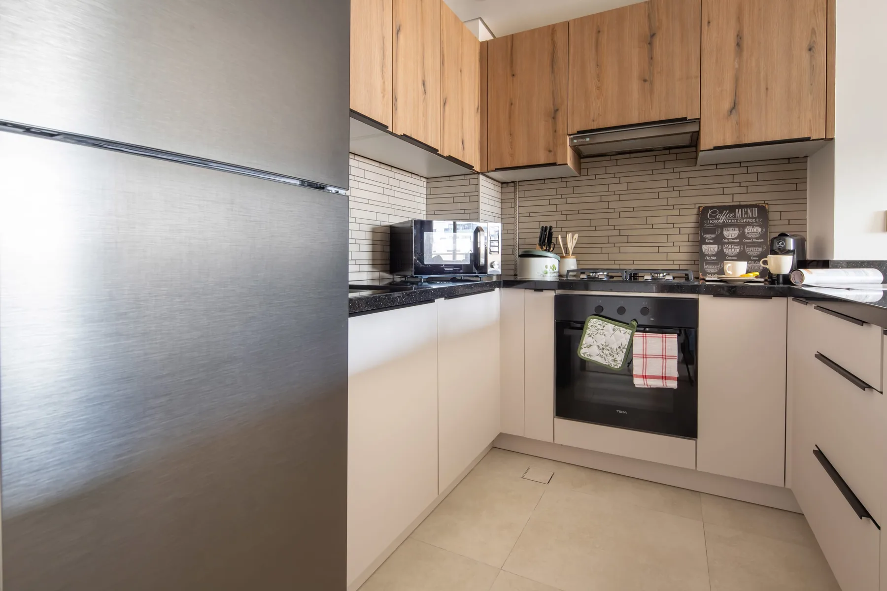 Una cocina moderna con gabinetes de madera, salpicadero de azulejos y horno integrado.