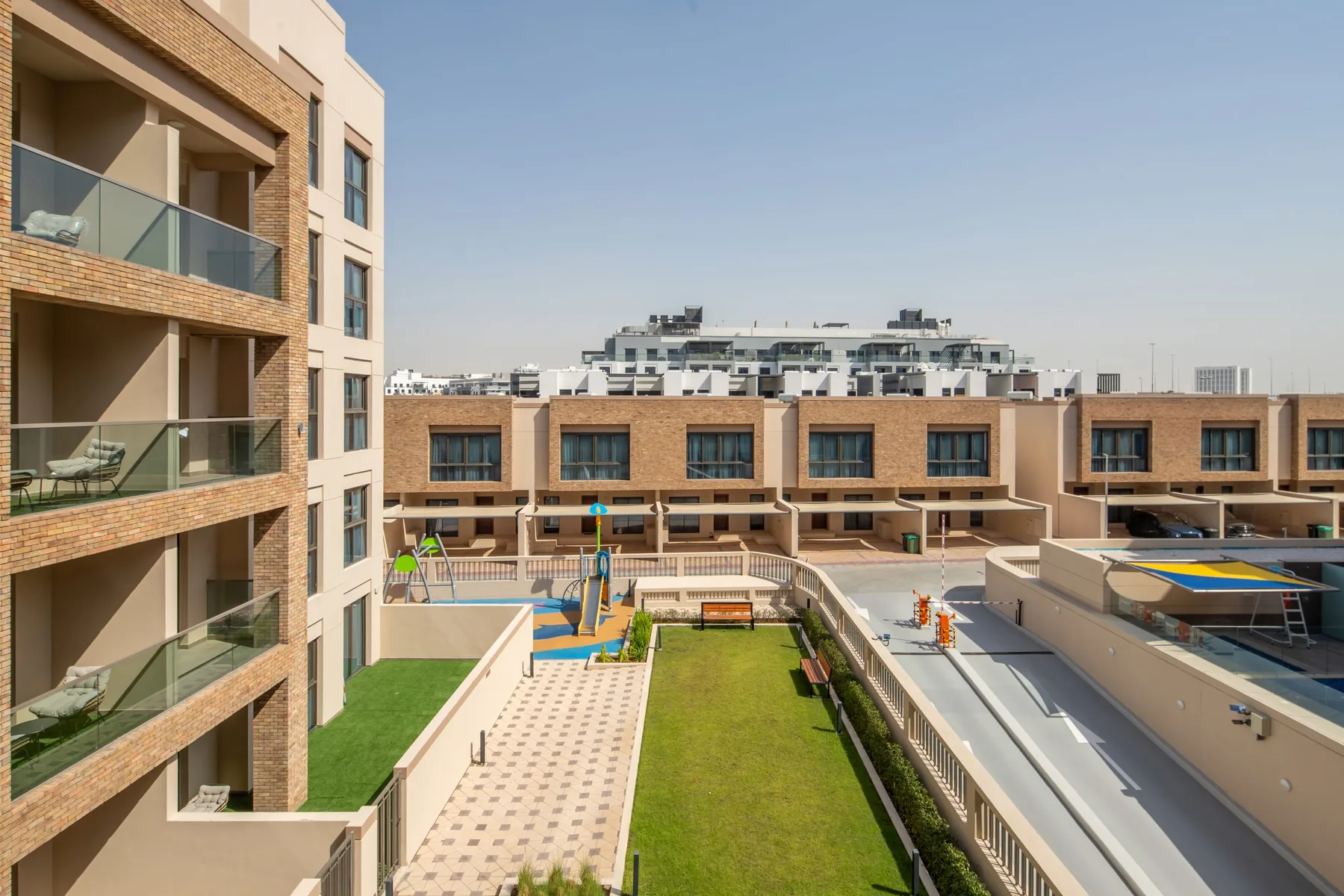 Un patio con césped y caminos pavimentados entre edificios de apartamentos.