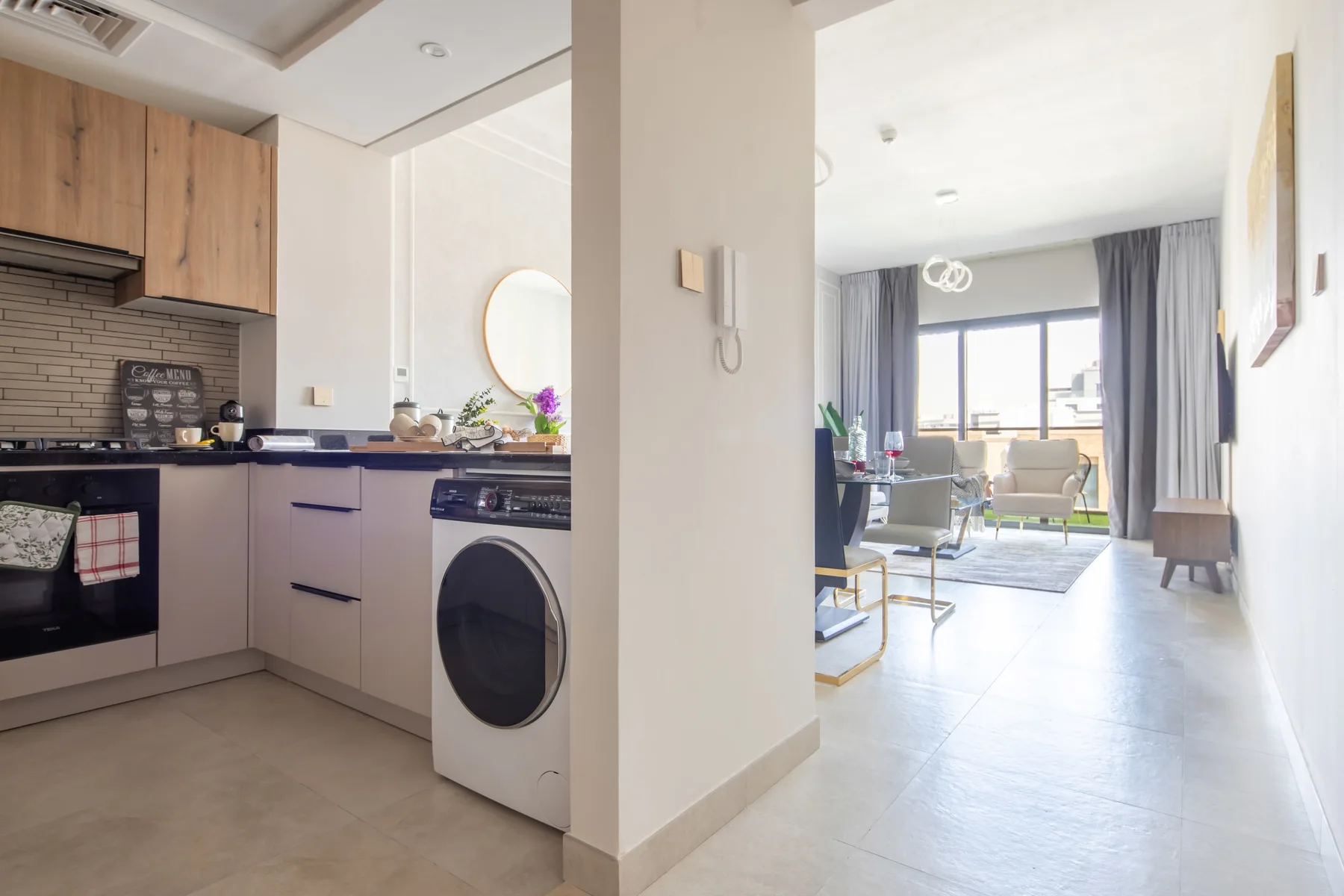 Una cocina compacta da a una sala luminosa con asientos junto a grandes ventanas.