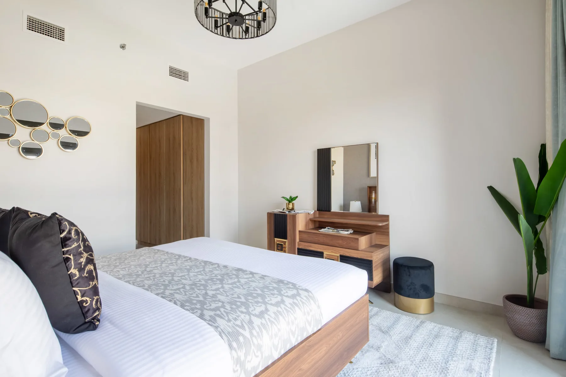 Un dormitorio luminoso con una cama, una cómoda de madera y una planta en maceta.