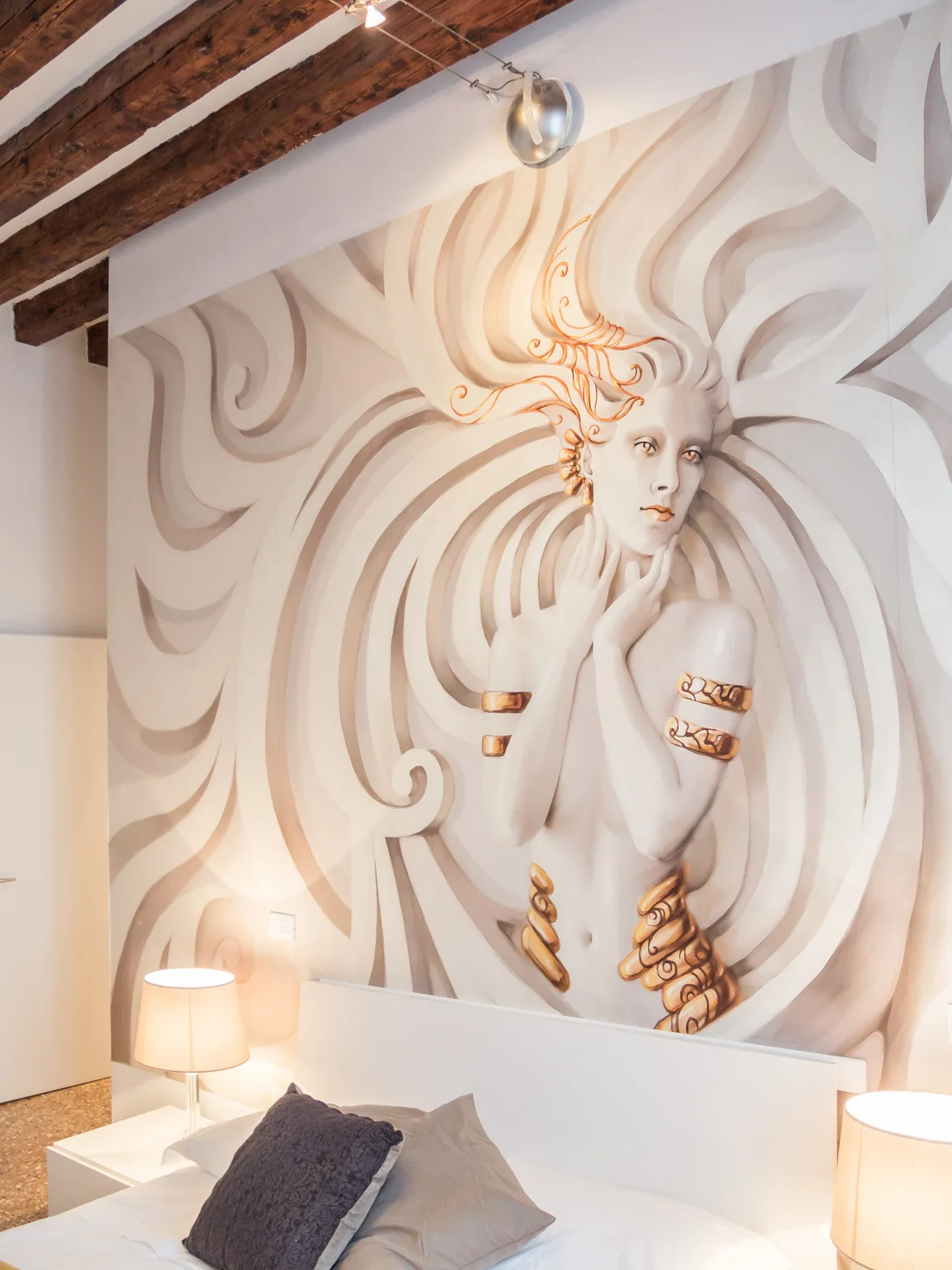 Un dormitorio con un gran mural de una figura estilizada detrás de la cama.