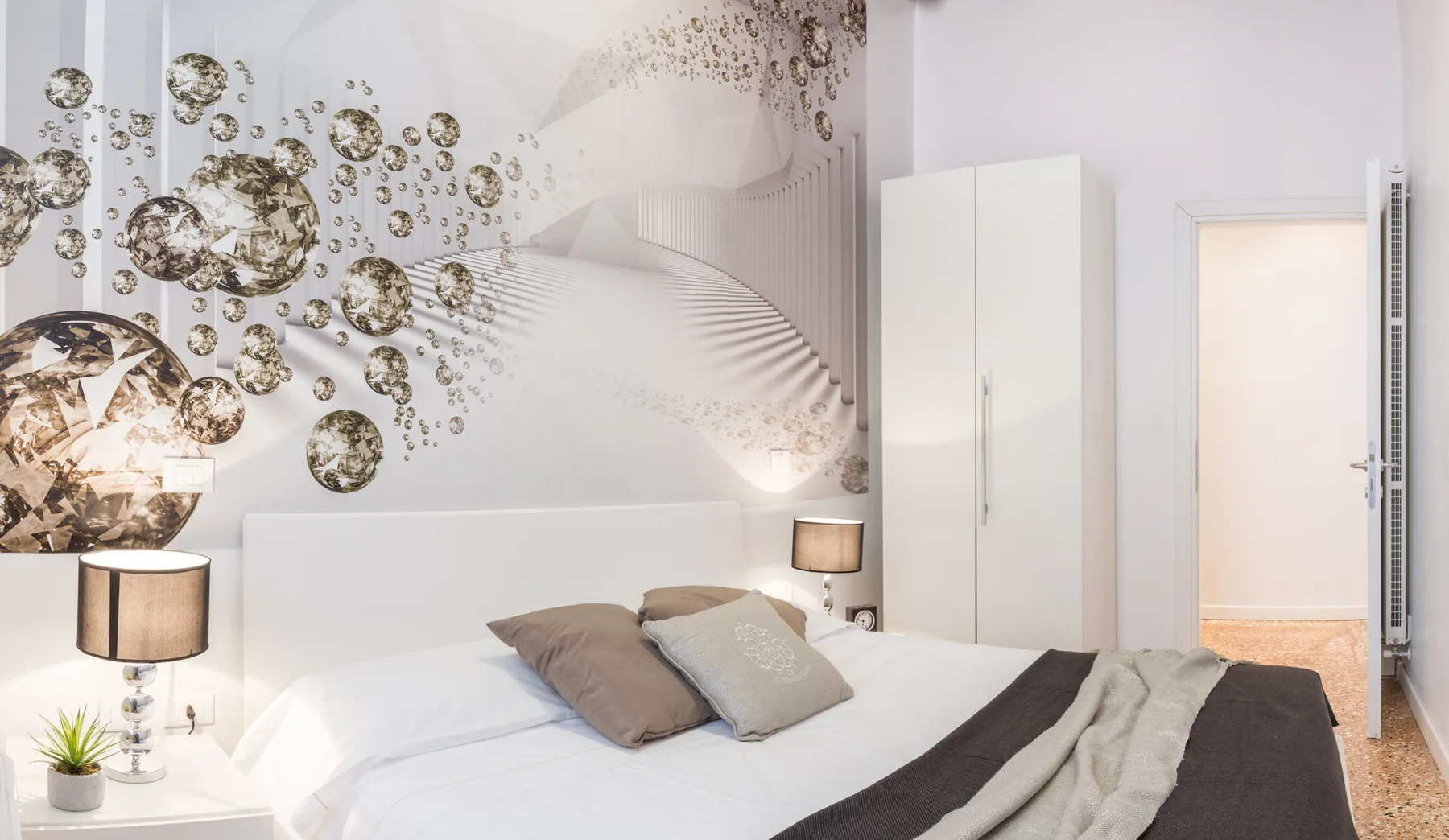 Un dormitorio luminoso con una cama, lámparas de mesita y arte abstracto en la pared.