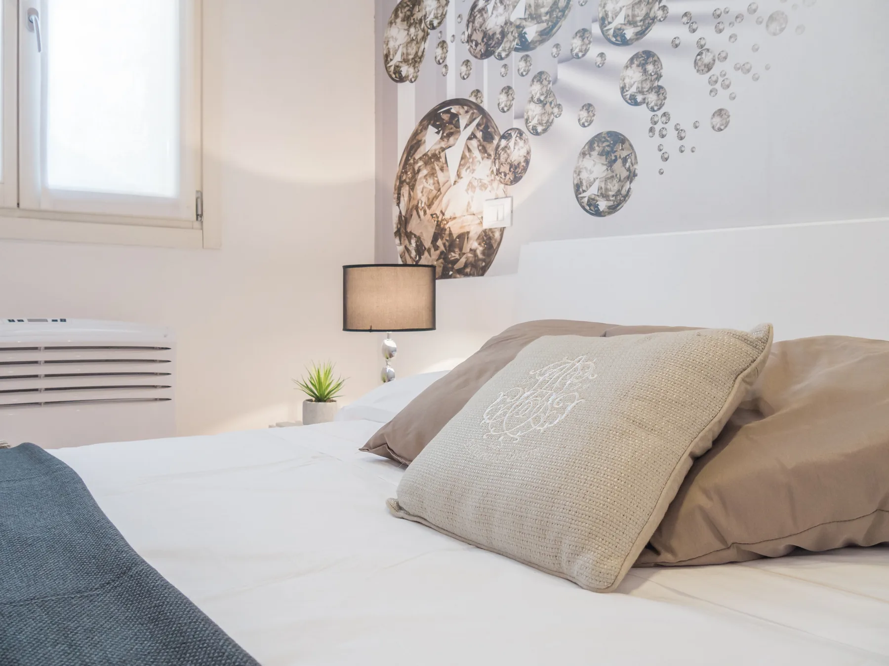 Un dormitorio luminoso con una cama bien hecha y arte decorativo en la pared.