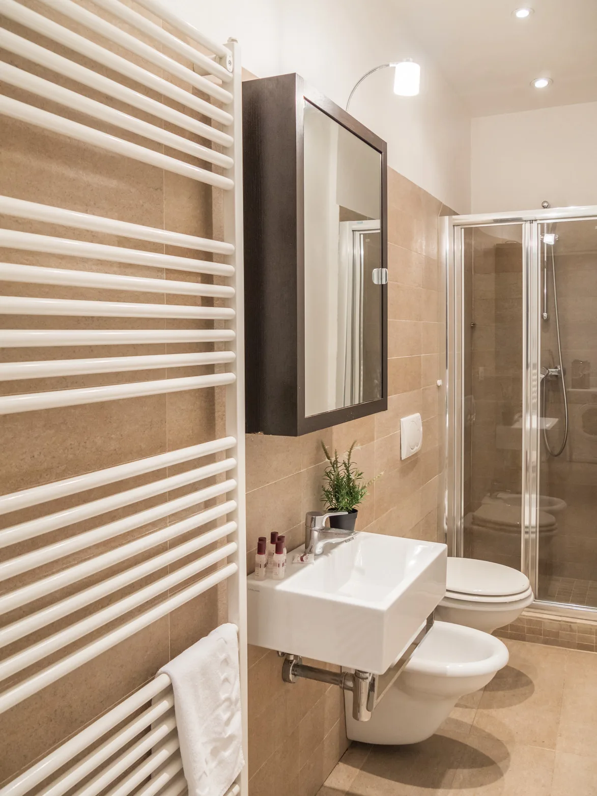 Un baño con lavabo suspendido, espejo y ducha de vidrio.