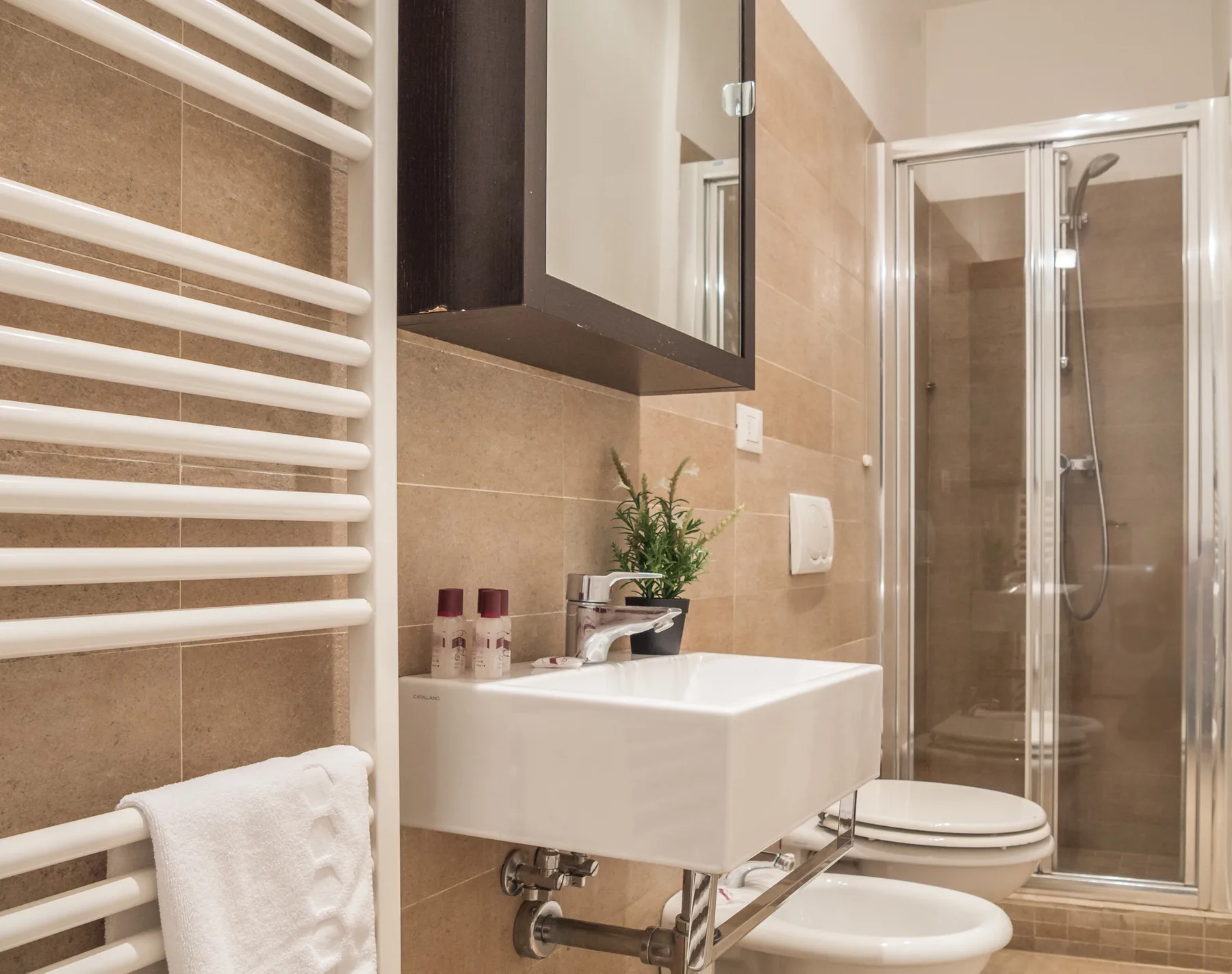 Un baño alicatado con lavabo, inodoro y ducha de vidrio.