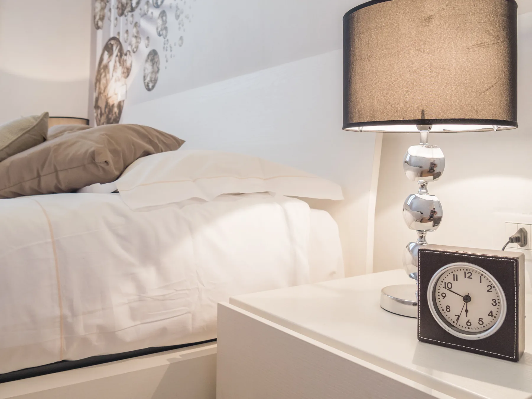 Un dormitorio con una cama tendida y una mesita de noche con una lámpara.