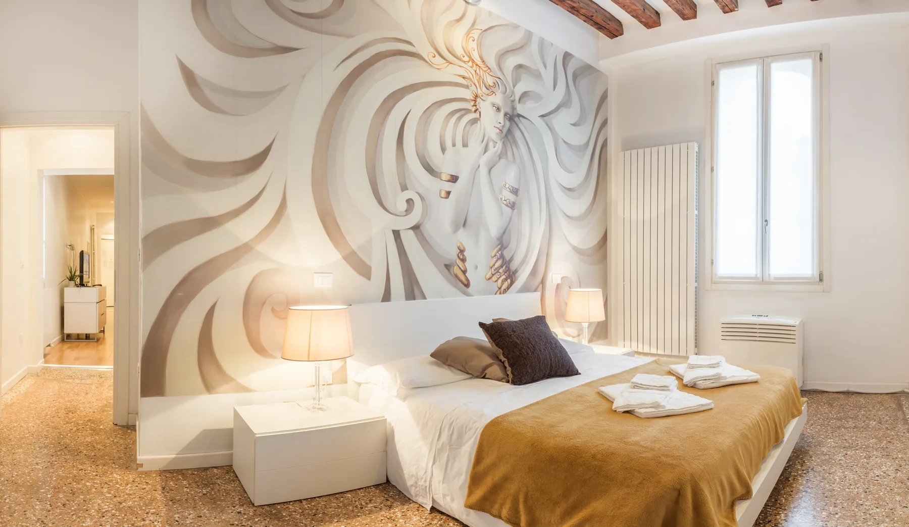 Un dormitorio con una cama frente a un gran mural decorativo.