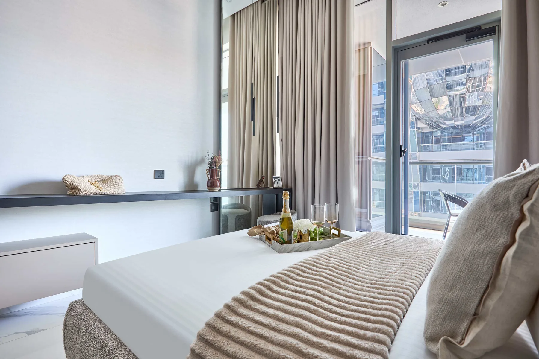 Un dormitorio luminoso con una cama tendida y cortinas de suelo a techo.