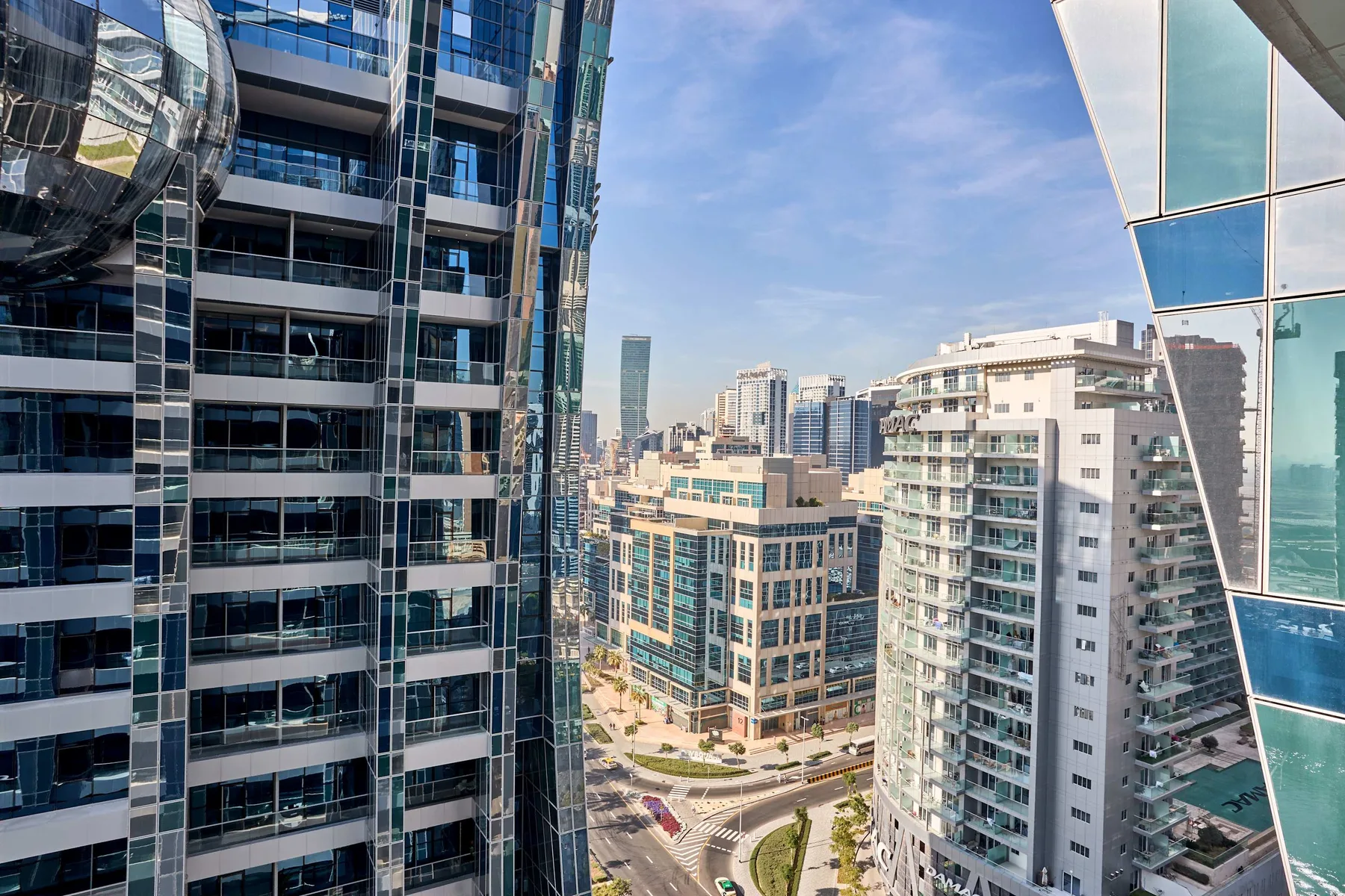 Vista de la ciudad entre edificios modernos de gran altura bajo un cielo despejado.