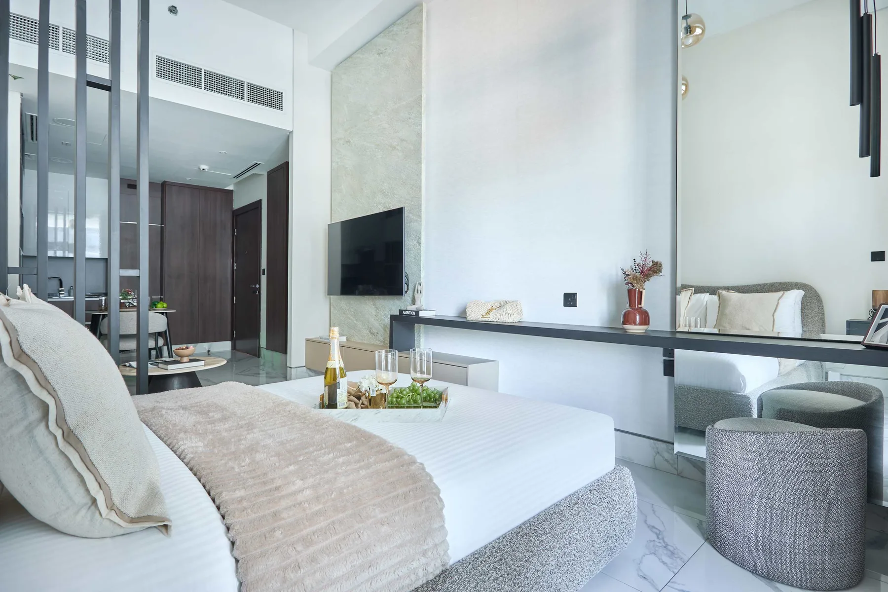 Un dormitorio luminoso con cama, televisor en la pared y zona de estar.