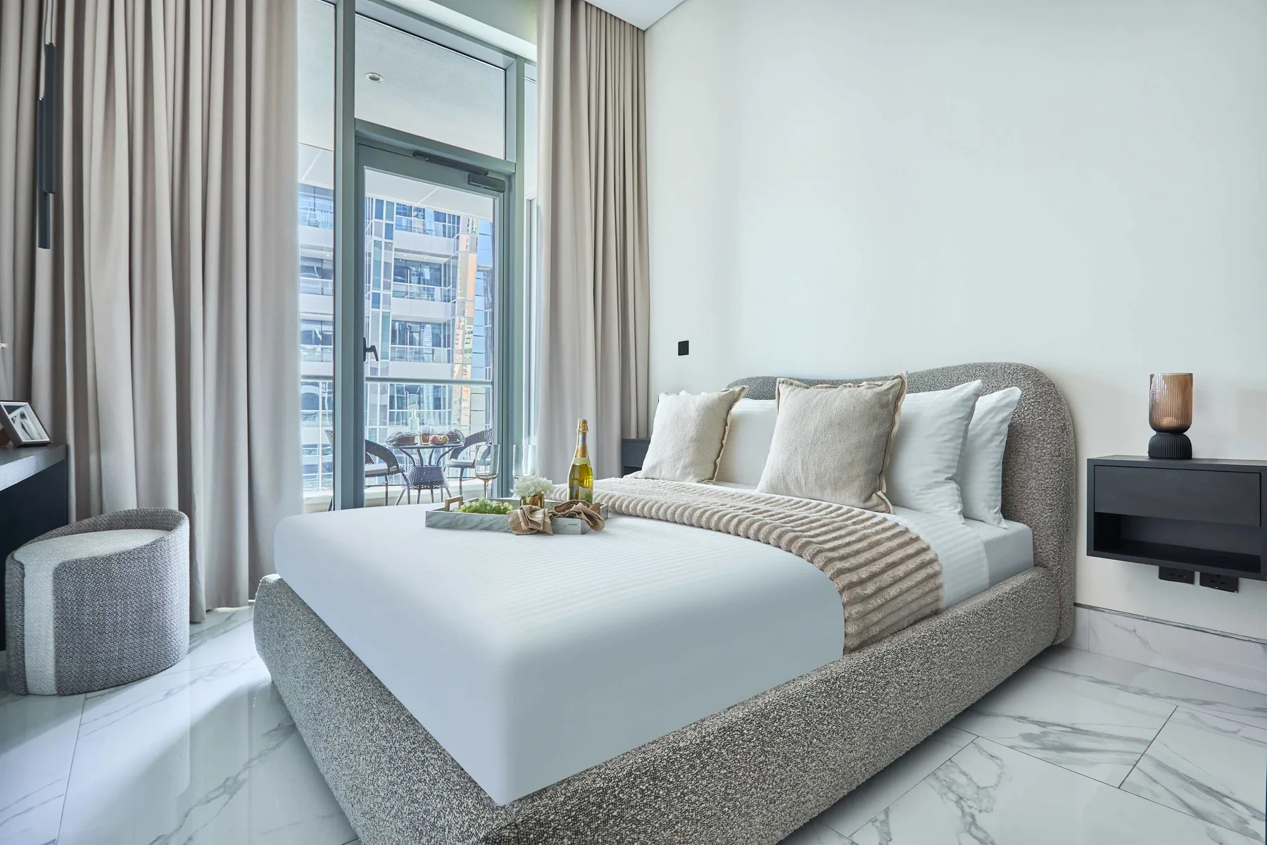 Un dormitorio con una cama junto a una ventana alta y cortinas.