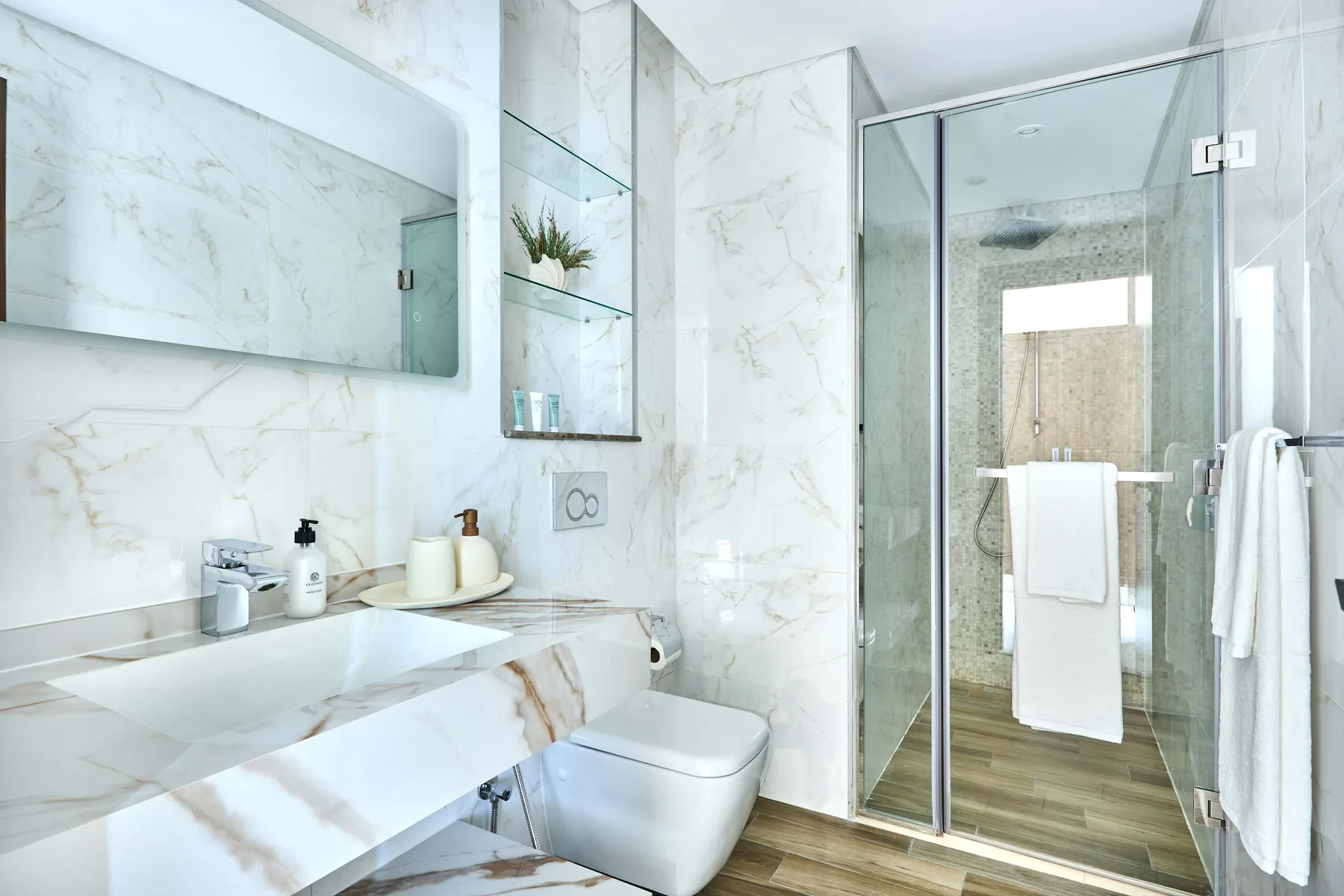 Un baño luminoso con un lavabo amplio y una ducha con mampara de vidrio.