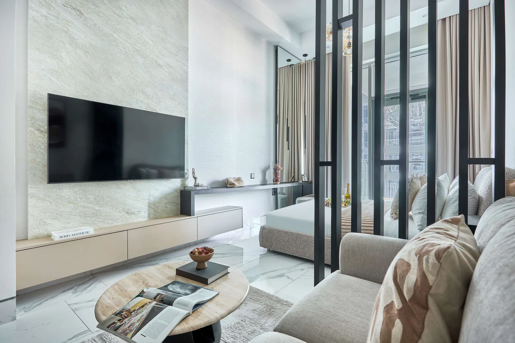 Una sala luminosa con televisor en la pared y asientos junto a ventanales de piso a techo.