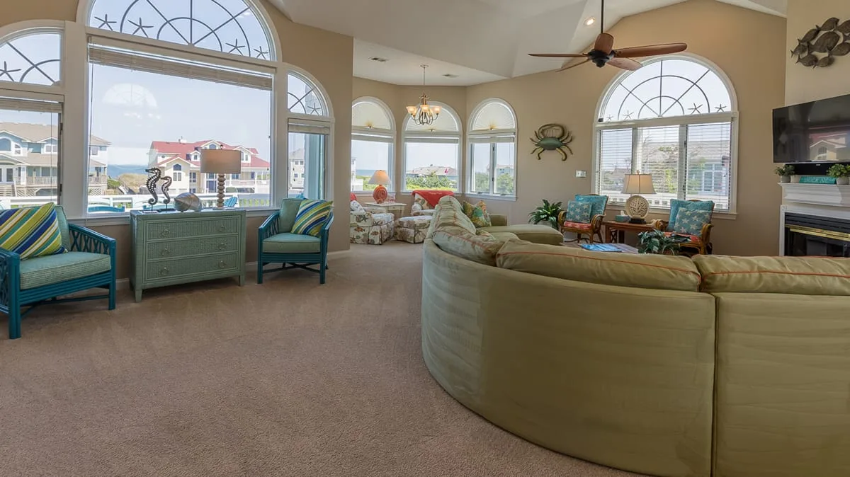Una sala de estar amplia con asientos curvos y grandes ventanas arqueadas.