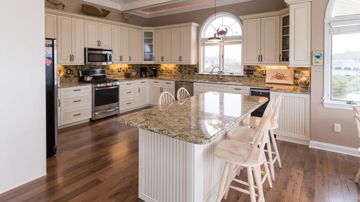 Una cocina luminosa con gabinetes blancos y una isla grande con asientos.