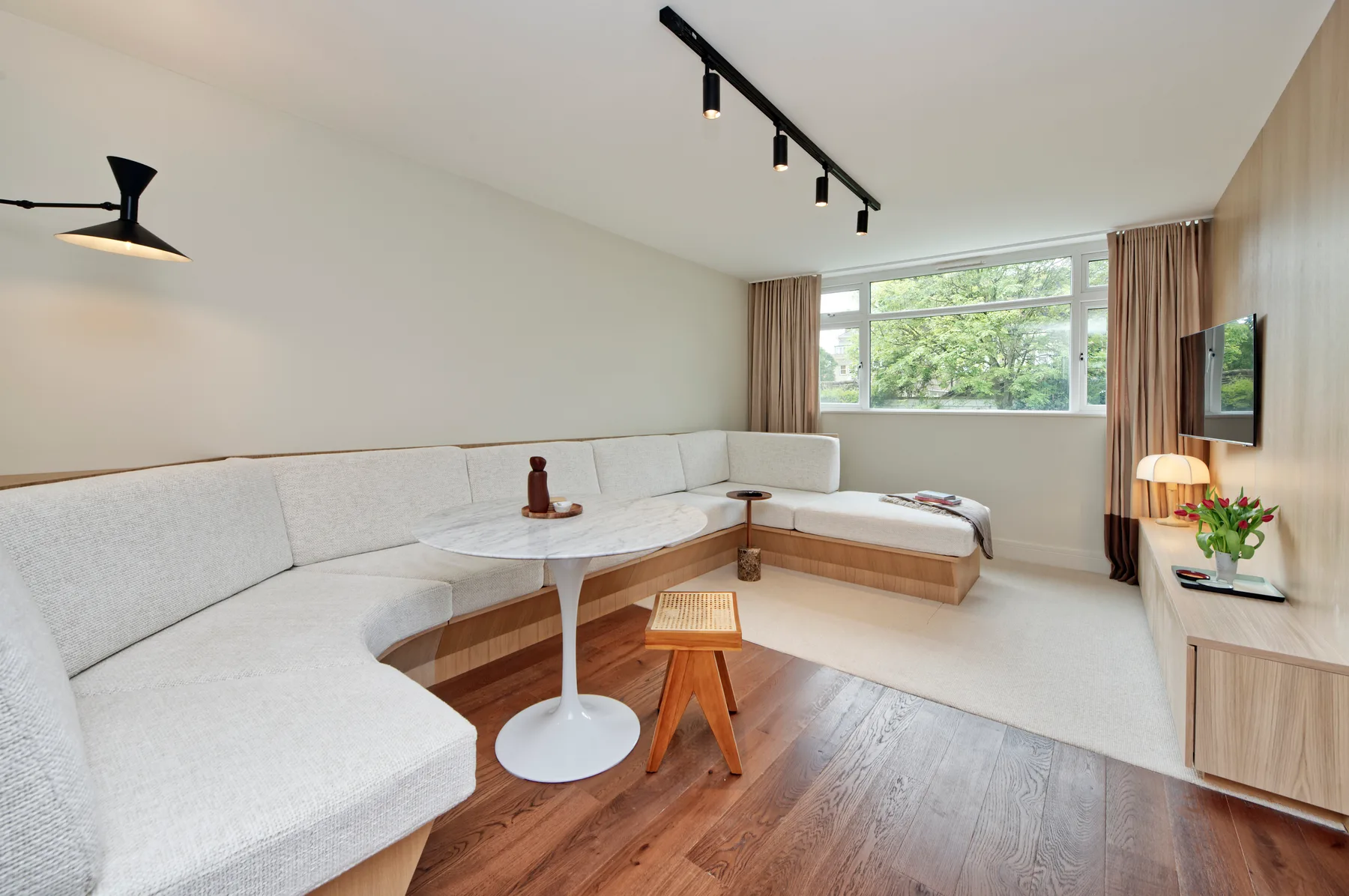 A bright living room with a large sectional seating area beside broad windows.