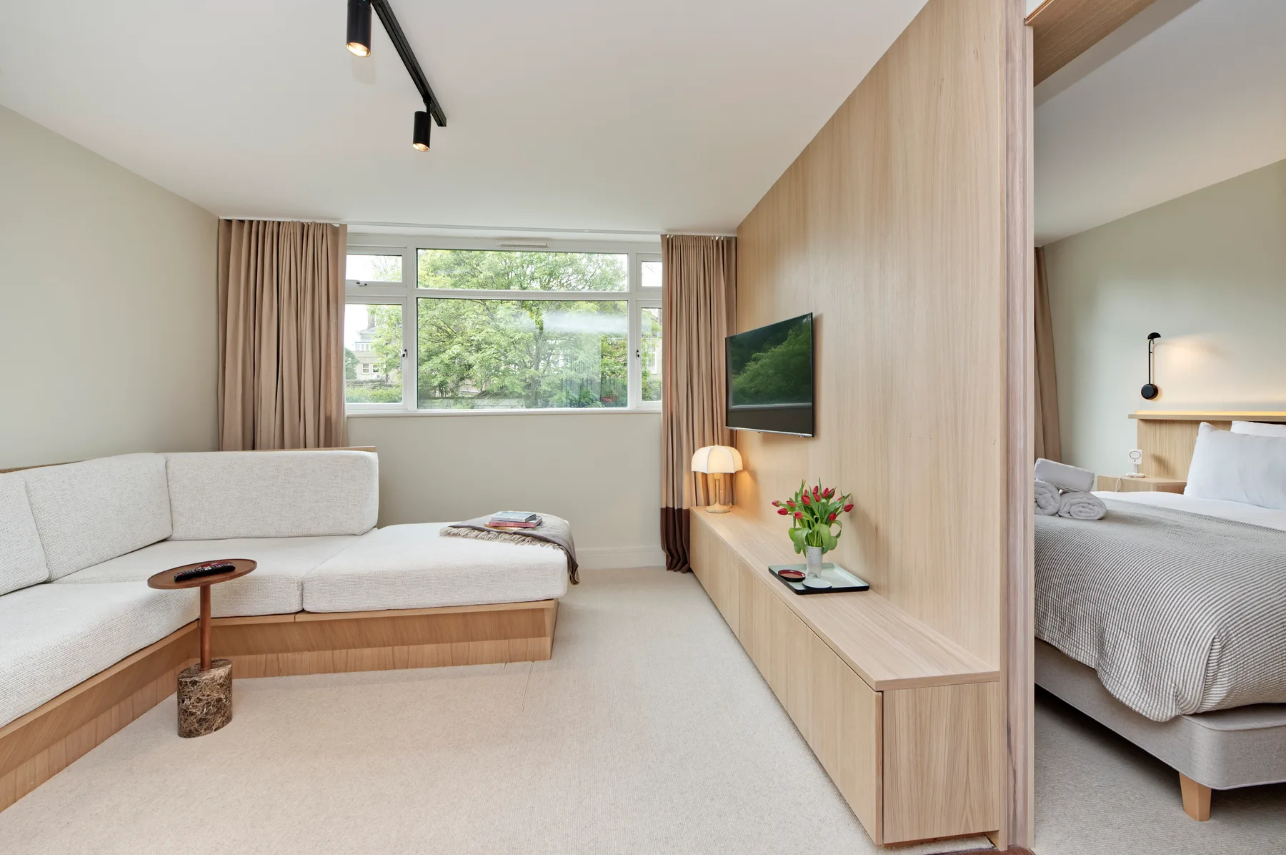 A bright living area with a sectional seating area, television, and large windows.