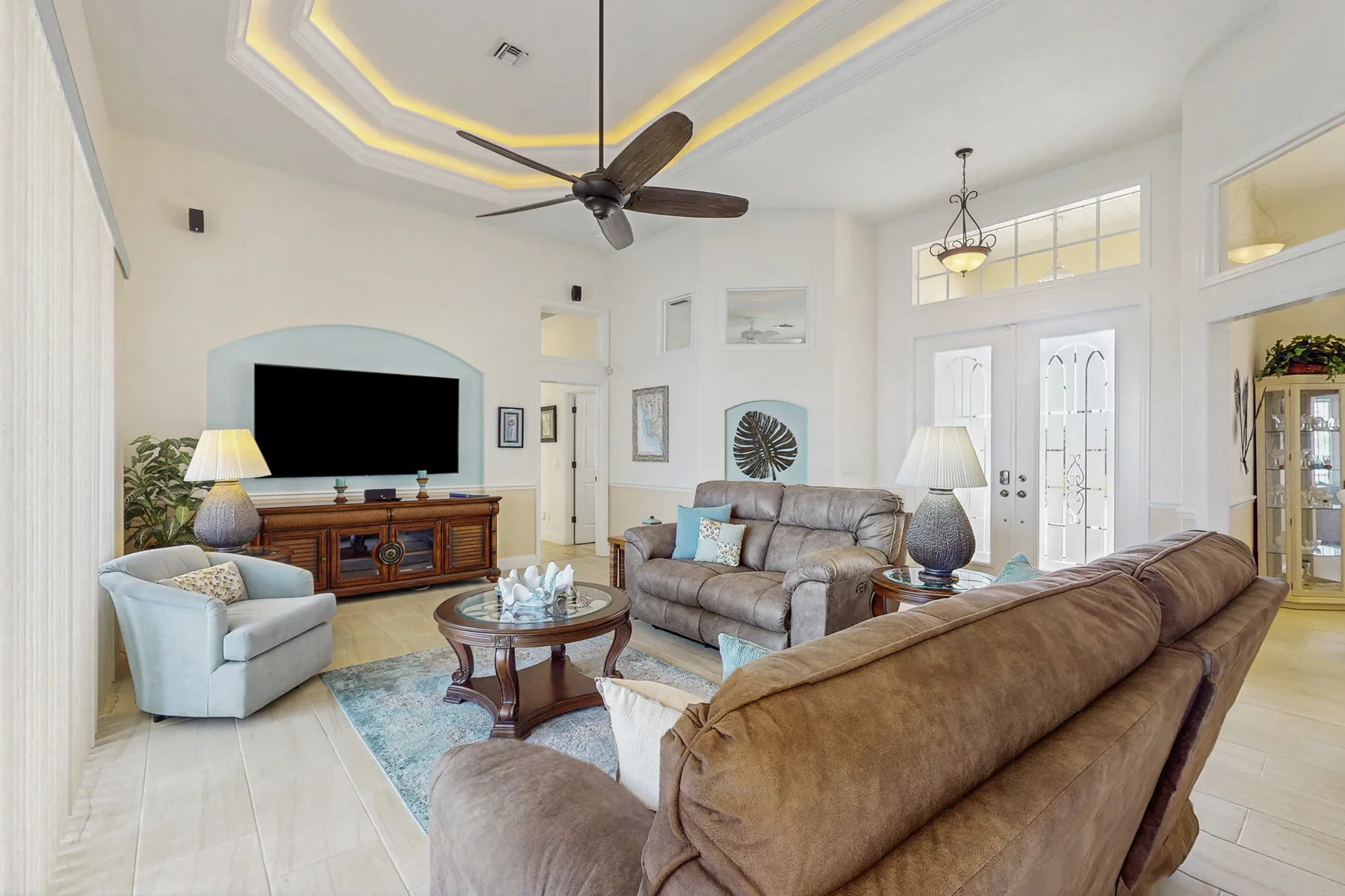 A bright living room with upholstered seating, a coffee table, and a television.