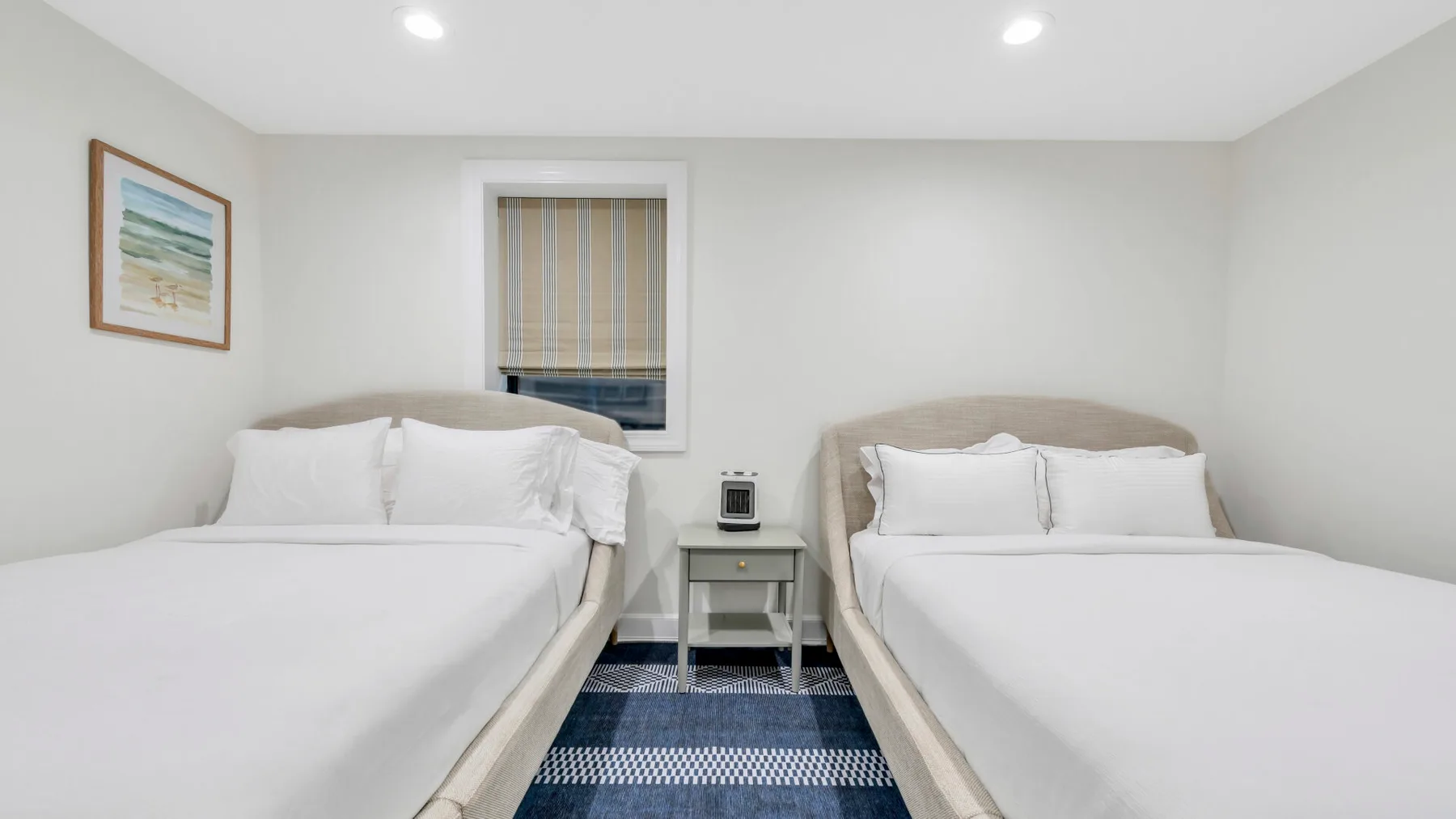 Un dormitorio con dos camas, una mesita de noche y una ventana.