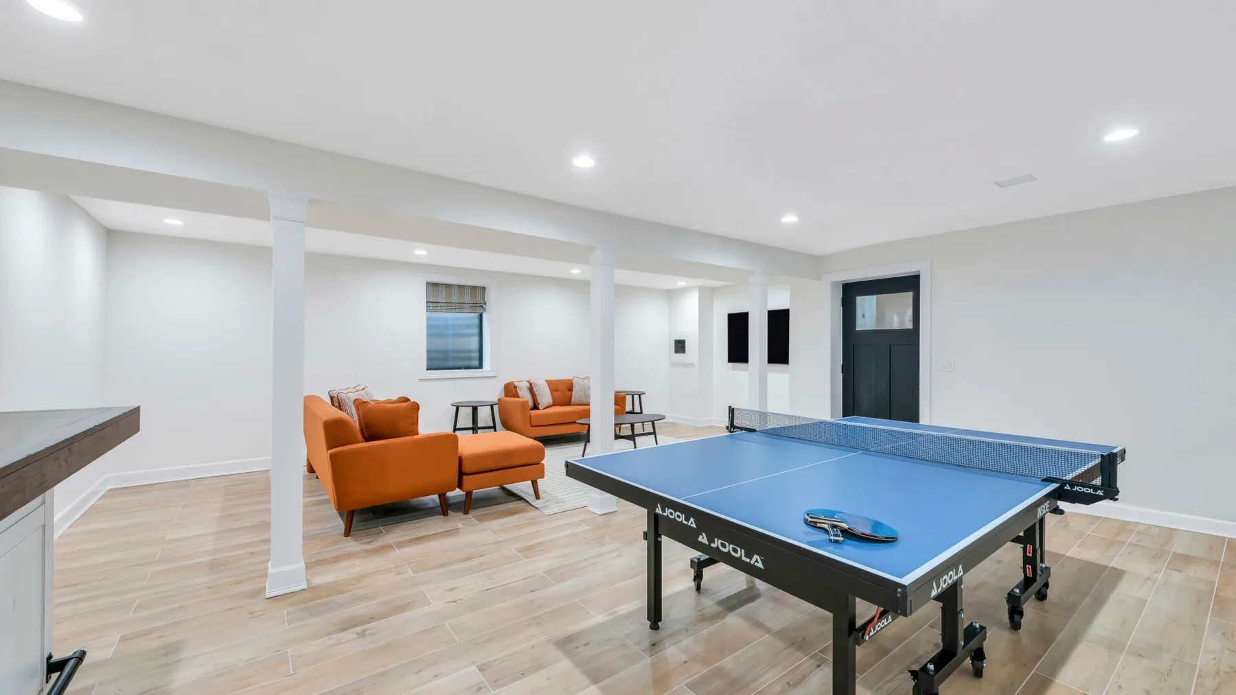 Una luminosa sala de recreación con una mesa de ping-pong azul y asientos naranjas.