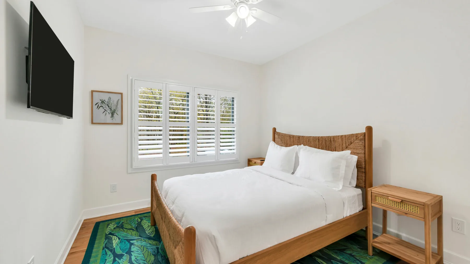 Un dormitorio luminoso con una cama de madera, ropa de cama blanca y una ventana con persianas.
