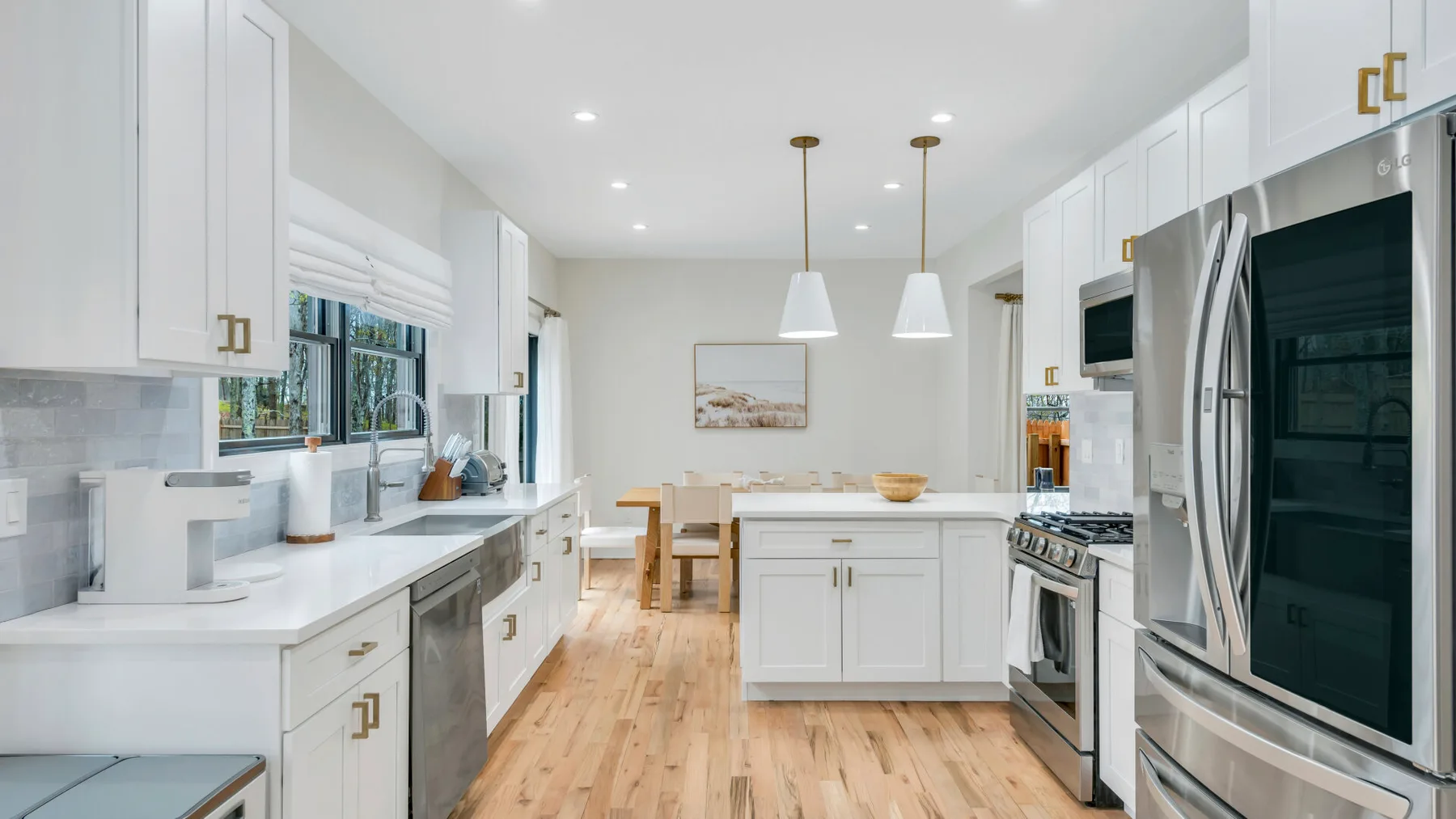 Una cocina luminosa con gabinetes blancos, encimeras largas y una mesa de comedor.
