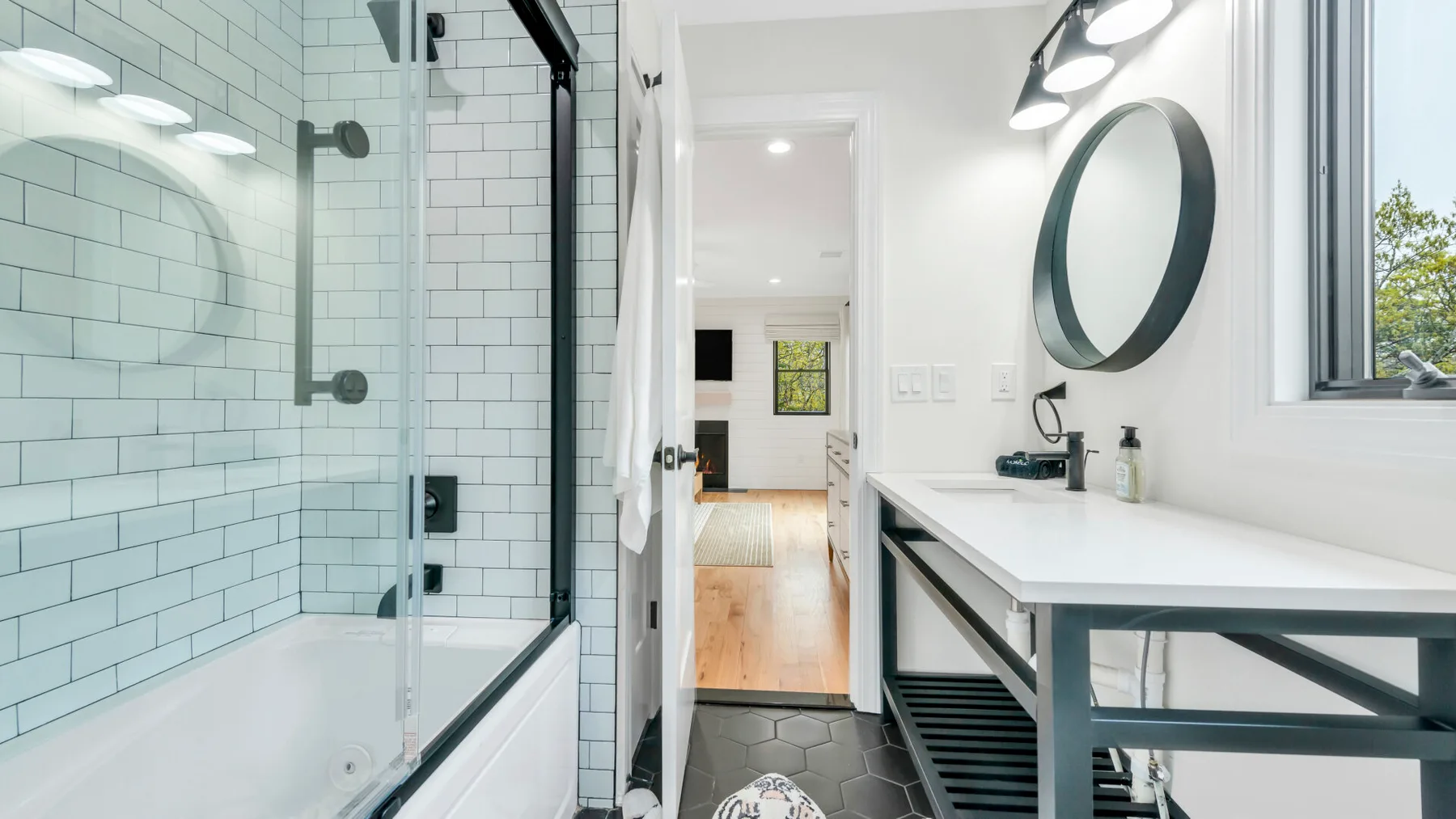 Un baño luminoso con ducha de cristal, bañera y un tocador largo.